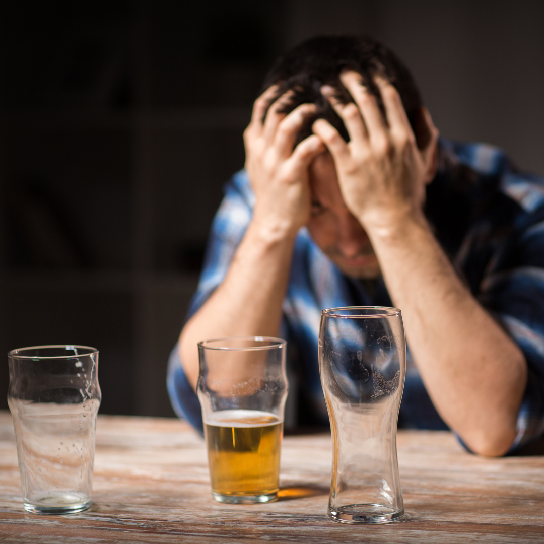Man holding his head because he is upset over the empty beer glasses in front of him
