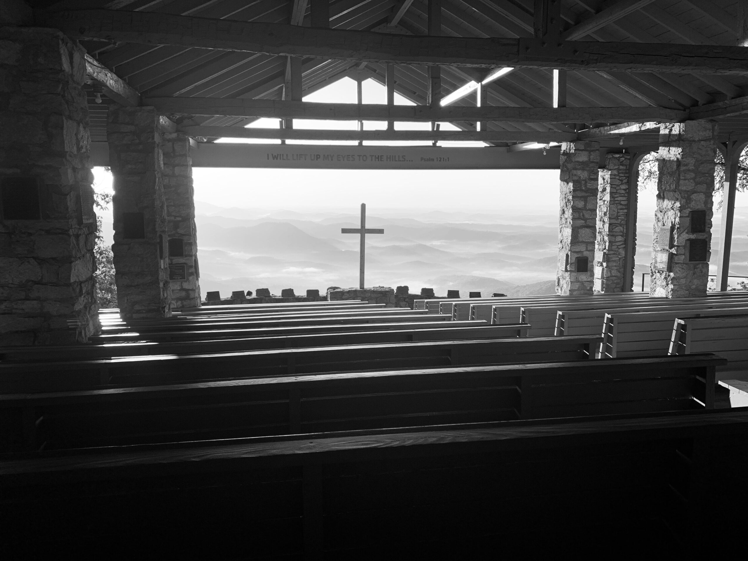Black and White Picture of Outdoor Sanctuary Looking at a Cross with Rolling Mountains in the Distance