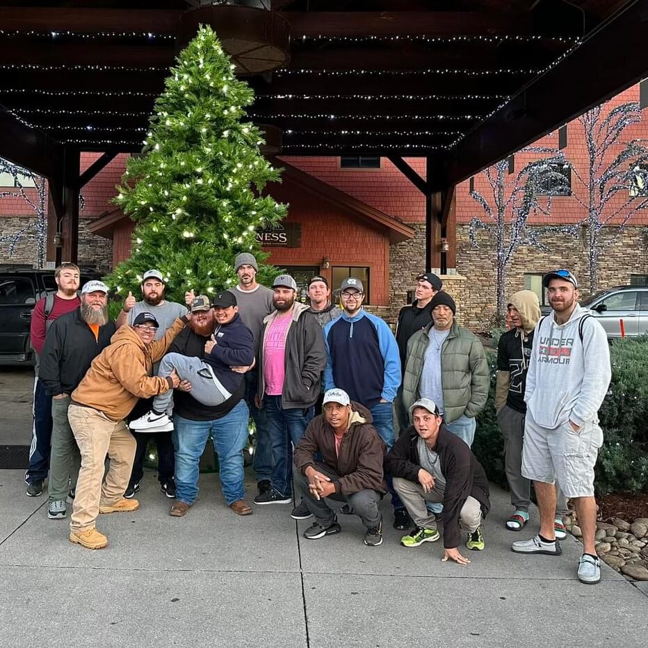 Group of men standing in front of a Christmas tree outside of a hotel
