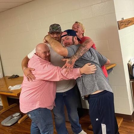 Men laughing and giving each other group hugs
